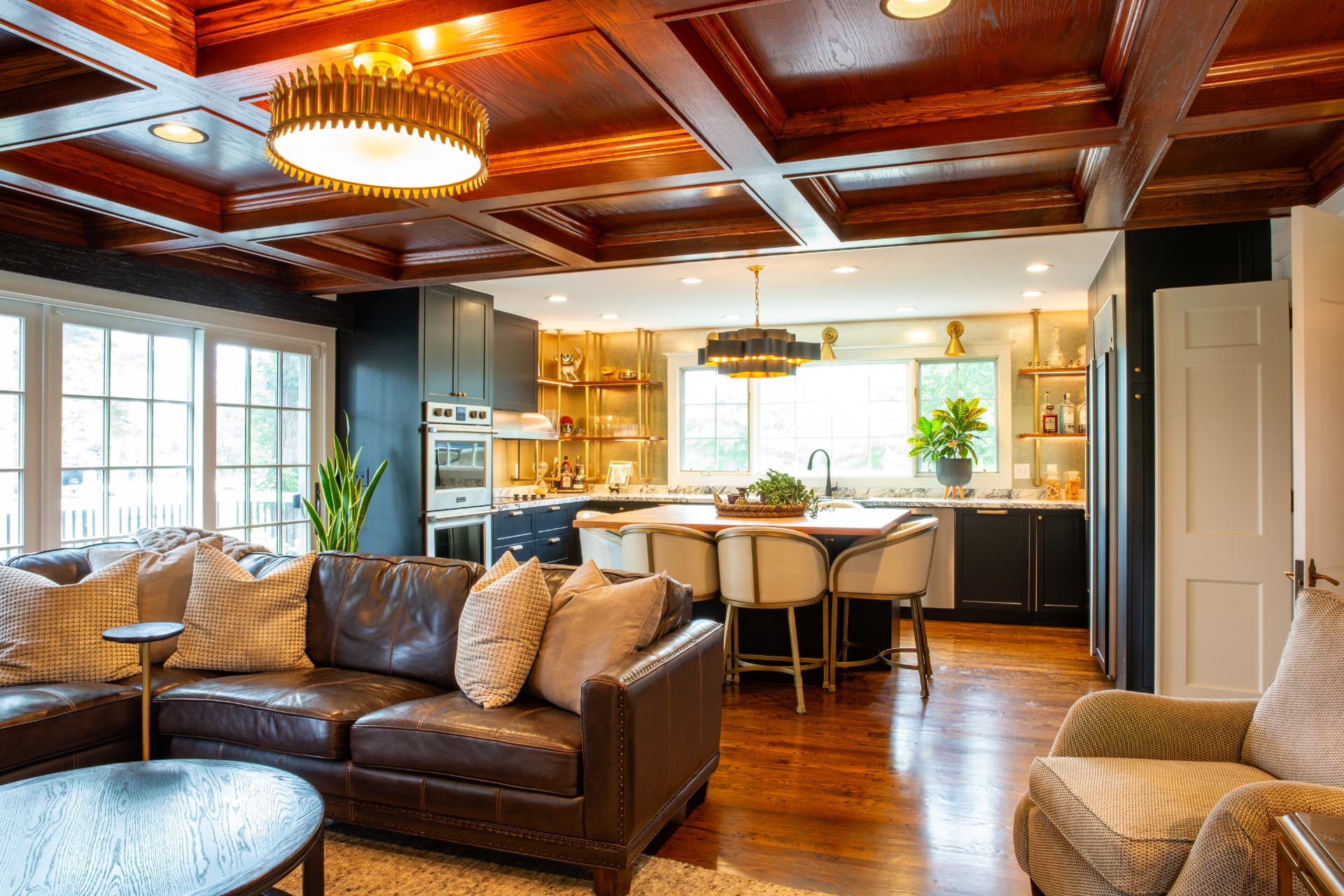 A Valentine Design living room — tufted leather sofa, warm wood paneling, and natural light